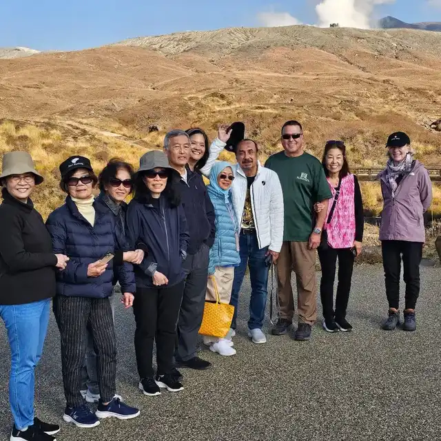 From the Autumn Tour in 2024, a group of tourists stop for a photo beneath Aso